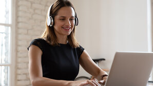 Woman sitting in front of laptop with headphones