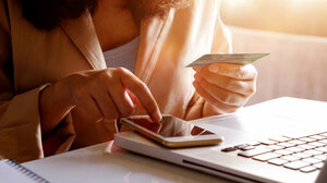 Woman sitting over laptop with her cell phone and ID card