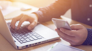 Person operates laptop and smartphone at the same time