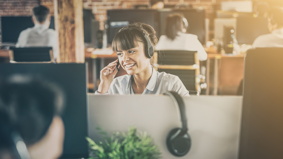 Woman sitting smiling with headphones in support office